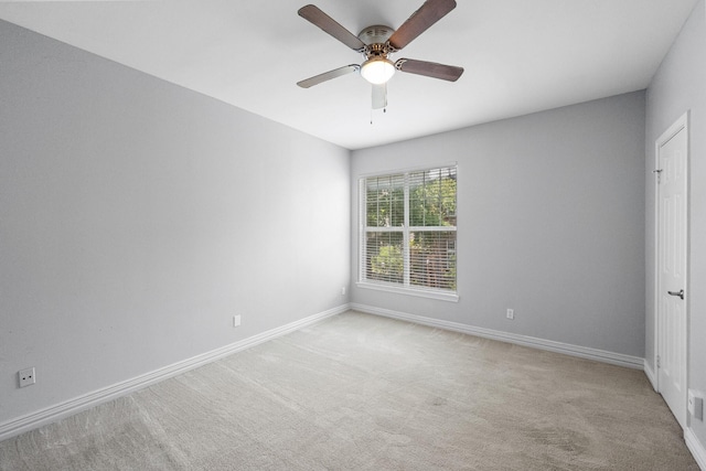 empty room featuring a ceiling fan, baseboards, and light carpet