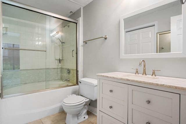 bathroom featuring tile patterned flooring, combined bath / shower with glass door, toilet, and vanity