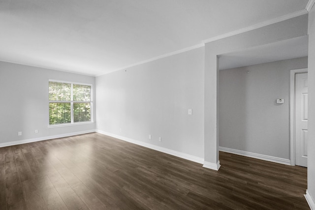 empty room with dark wood-style floors, baseboards, and ornamental molding