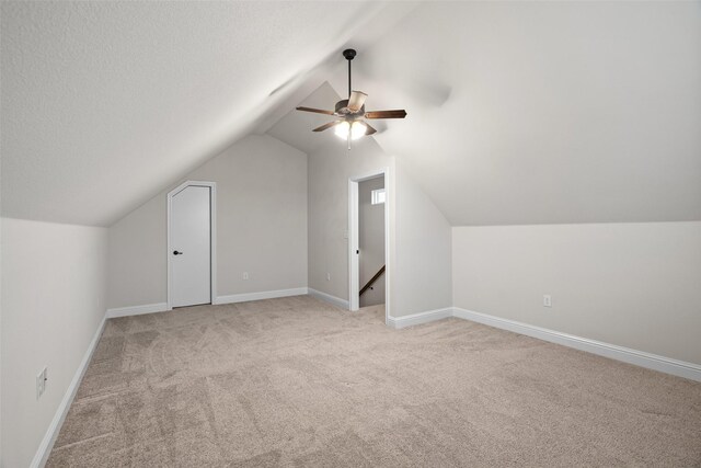 bonus room featuring light carpet, a textured ceiling, vaulted ceiling, and ceiling fan