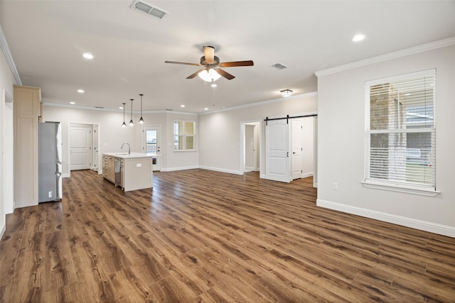 unfurnished living room featuring ceiling fan, crown molding, dark wood-type flooring, sink, and a barn door