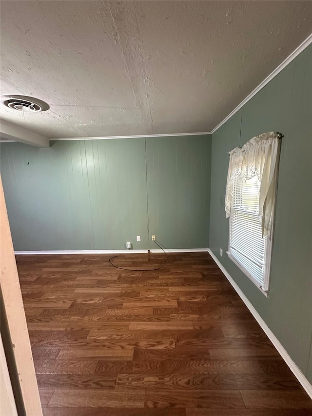 spare room with crown molding, dark hardwood / wood-style floors, and a textured ceiling