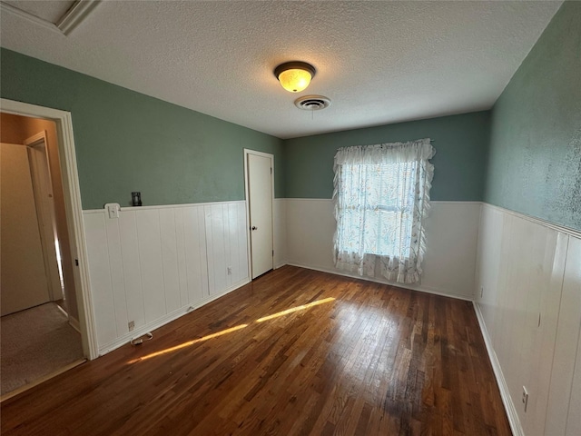 spare room with dark hardwood / wood-style floors and a textured ceiling