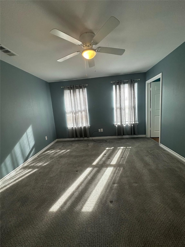 spare room with ceiling fan, plenty of natural light, and dark carpet