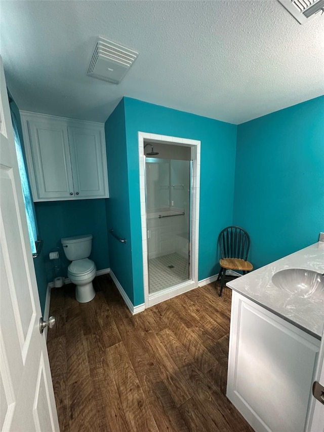 bathroom featuring toilet, an enclosed shower, a textured ceiling, vanity, and hardwood / wood-style flooring