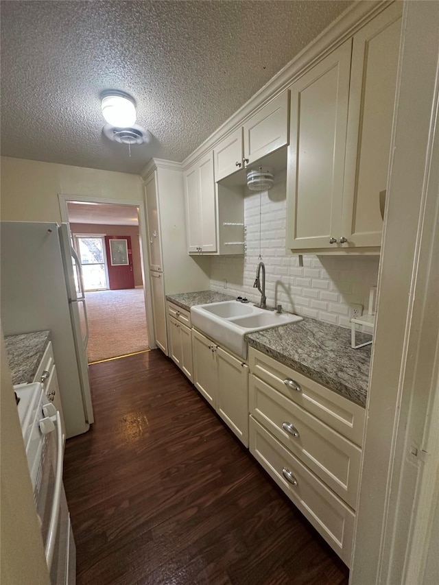 kitchen with sink, range, white refrigerator, light stone countertops, and dark hardwood / wood-style flooring