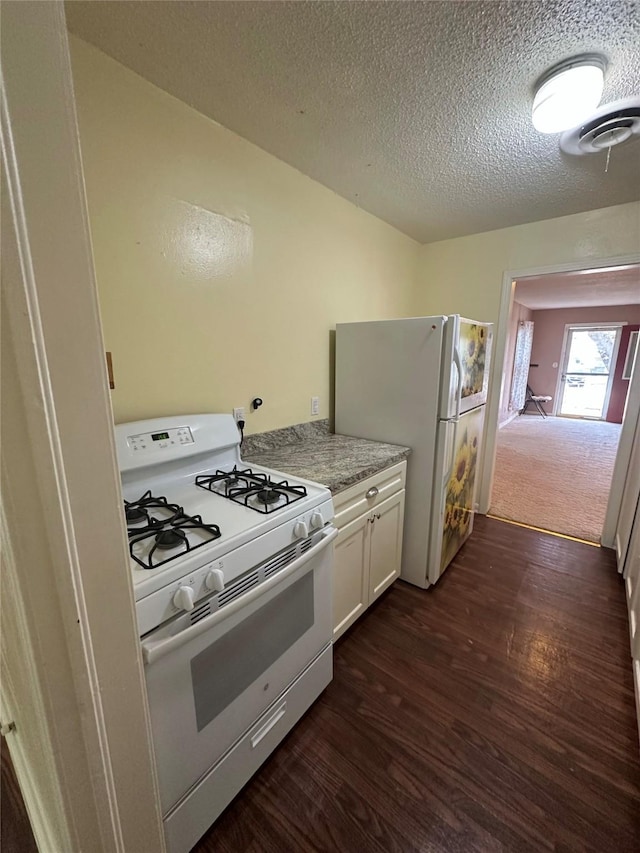 kitchen featuring white cabinetry, white appliances, dark wood-type flooring, and a textured ceiling