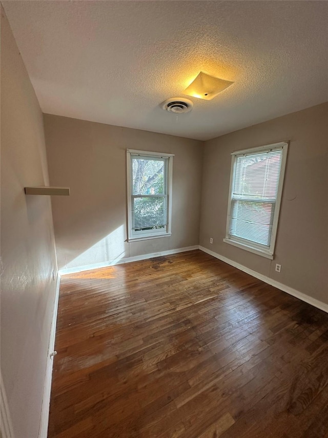 empty room featuring dark wood-type flooring and a textured ceiling