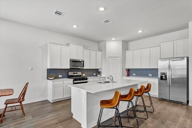 kitchen with sink, white cabinets, light hardwood / wood-style flooring, and appliances with stainless steel finishes