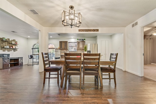 dining area featuring a chandelier, a textured ceiling, and dark wood-type flooring