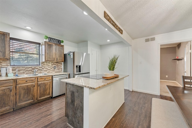 kitchen with a center island, stainless steel appliances, a textured ceiling, and sink