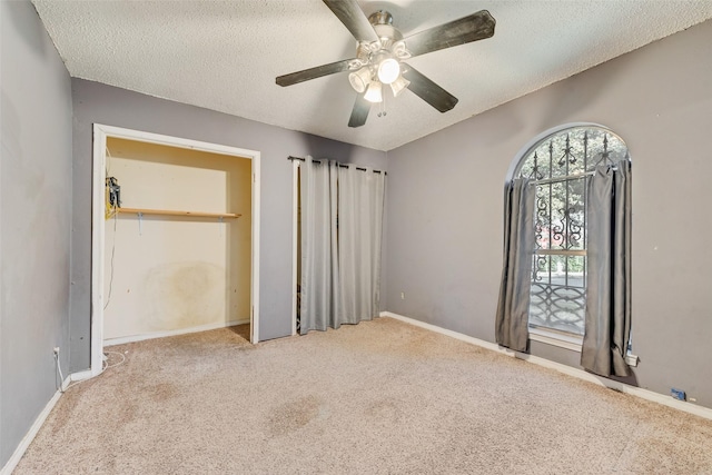 unfurnished bedroom featuring light carpet, a textured ceiling, and ceiling fan