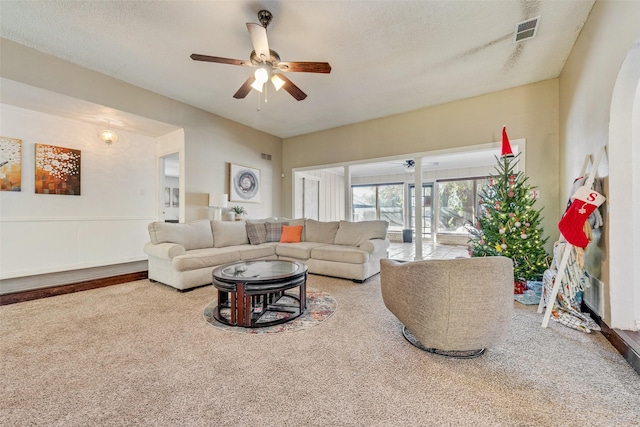 carpeted living room featuring ceiling fan and a textured ceiling