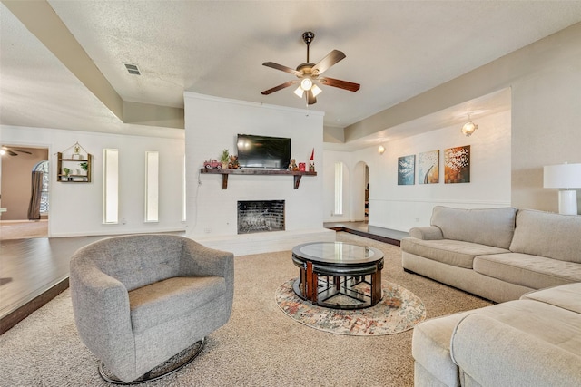 carpeted living room featuring ceiling fan and a textured ceiling