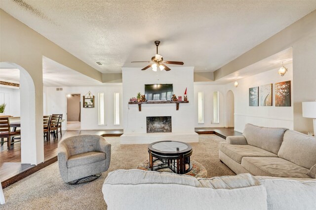 living room featuring hardwood / wood-style flooring, plenty of natural light, ceiling fan, and a textured ceiling