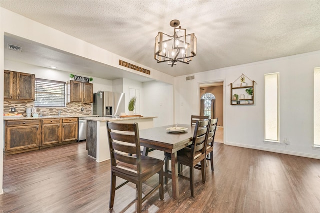 dining area with a chandelier, a textured ceiling, and dark hardwood / wood-style flooring