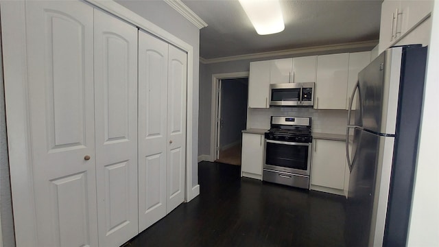 kitchen featuring backsplash, white cabinets, crown molding, dark hardwood / wood-style floors, and appliances with stainless steel finishes