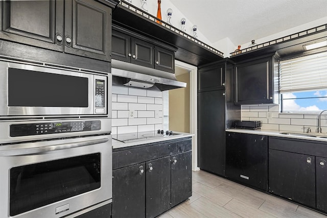 kitchen featuring lofted ceiling, backsplash, sink, a textured ceiling, and stainless steel appliances