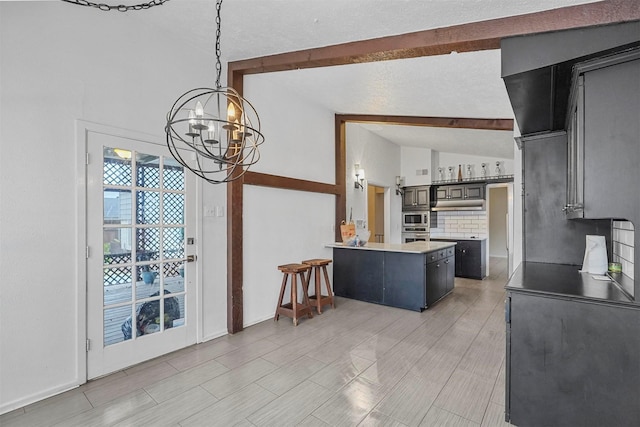 kitchen featuring backsplash, lofted ceiling with beams, decorative light fixtures, a notable chandelier, and a kitchen island