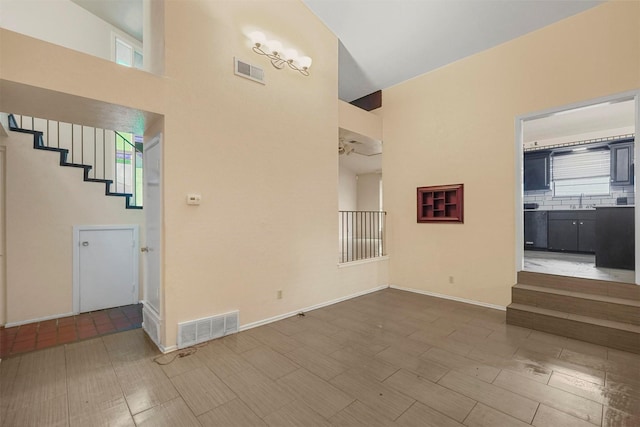 unfurnished living room featuring sink and high vaulted ceiling