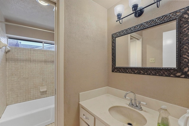 bathroom with vanity, tiled shower / bath combo, and a textured ceiling