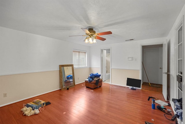 exercise room with ceiling fan, wood-type flooring, and a textured ceiling