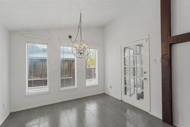 unfurnished dining area featuring dark hardwood / wood-style flooring, a textured ceiling, an inviting chandelier, and vaulted ceiling