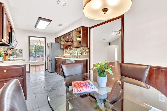 dining space featuring ceiling fan with notable chandelier, lofted ceiling, and sink