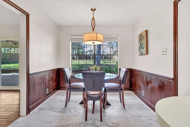 dining room with a textured ceiling and wood walls