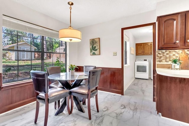 dining room featuring washer / clothes dryer, wooden walls, and a textured ceiling