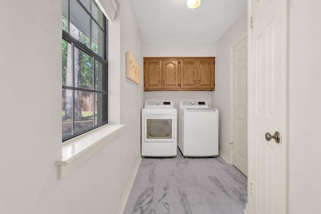 laundry area with cabinets, a textured ceiling, and washer and clothes dryer