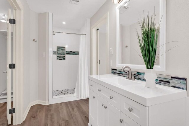 bathroom with hardwood / wood-style floors, a shower with curtain, backsplash, and vanity