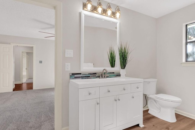 bathroom with ceiling fan, hardwood / wood-style floors, vanity, and toilet