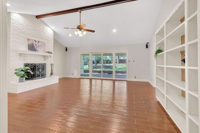 unfurnished living room with ceiling fan, beam ceiling, wood-type flooring, and a brick fireplace