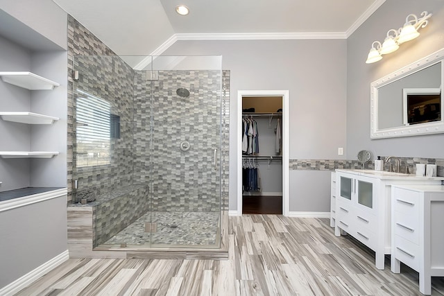 full bath featuring a stall shower, ornamental molding, wood finished floors, a spacious closet, and vanity