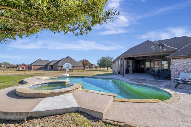 view of swimming pool featuring a yard, a pool with connected hot tub, a patio, and fence