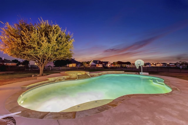 view of pool with fence and a pool with connected hot tub