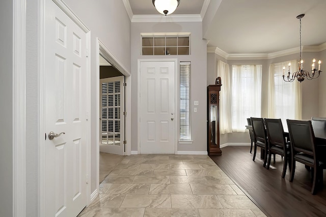 foyer entrance featuring light wood-type flooring, crown molding, and a notable chandelier