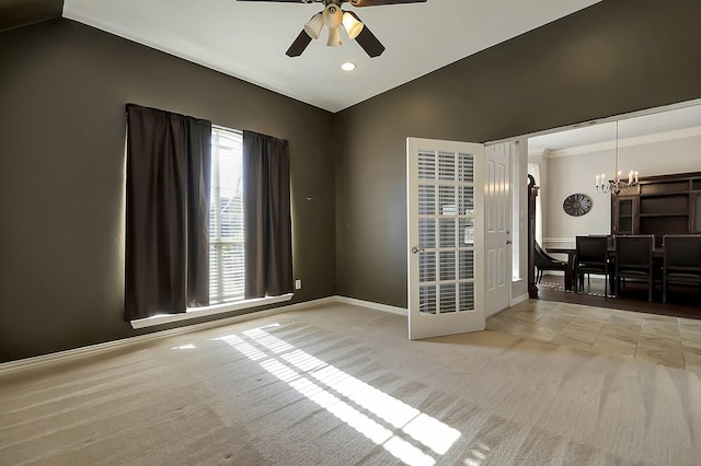 empty room featuring light carpet, ceiling fan with notable chandelier, and vaulted ceiling