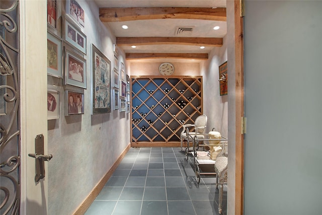 wine area featuring dark tile patterned flooring and beam ceiling