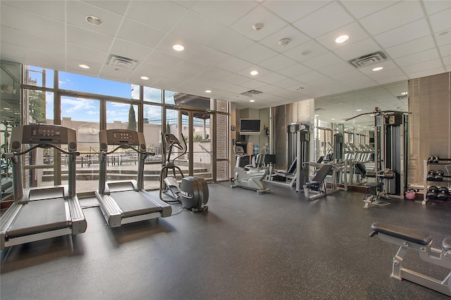 gym featuring a drop ceiling and a wall of windows