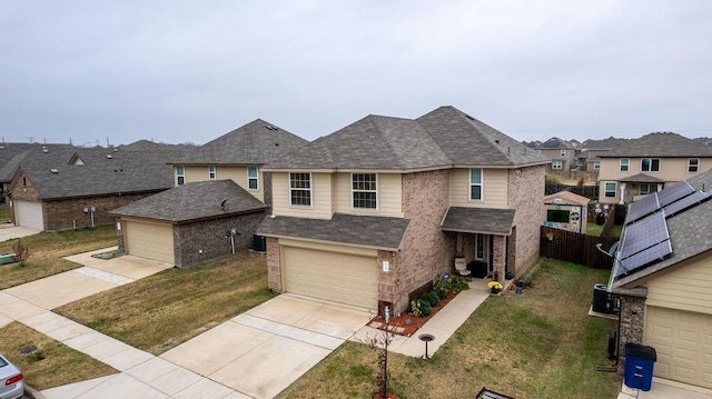 view of front of house with central AC, a garage, and a front lawn