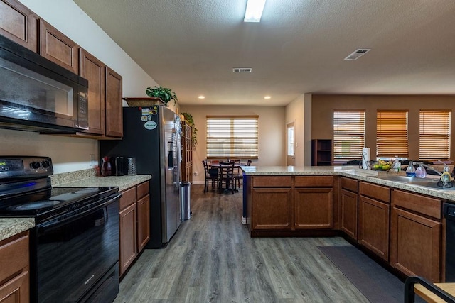 kitchen featuring sink, light hardwood / wood-style flooring, plenty of natural light, and black appliances