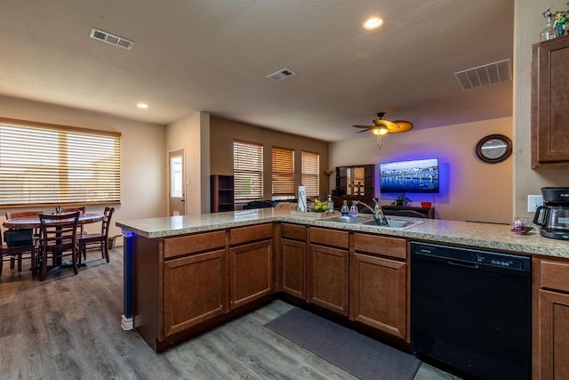 kitchen with sink, hardwood / wood-style flooring, black dishwasher, a healthy amount of sunlight, and kitchen peninsula