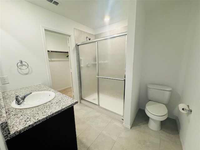 bathroom featuring walk in shower, vanity, toilet, and tile patterned flooring