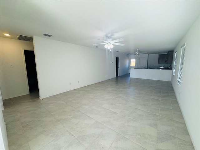 unfurnished living room featuring ceiling fan and a wealth of natural light