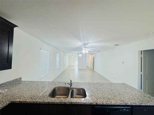 kitchen with light stone counters, ceiling fan, black dishwasher, and sink