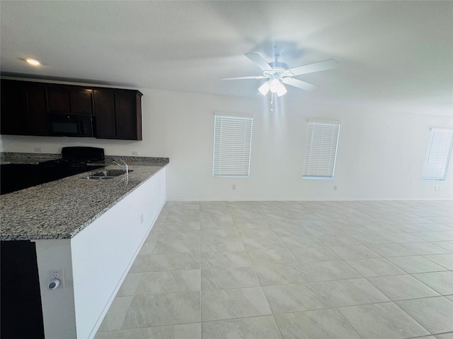 kitchen with stone counters, kitchen peninsula, sink, and black appliances