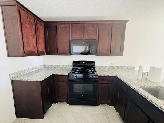 kitchen with light stone countertops, light tile patterned floors, black appliances, and a textured ceiling