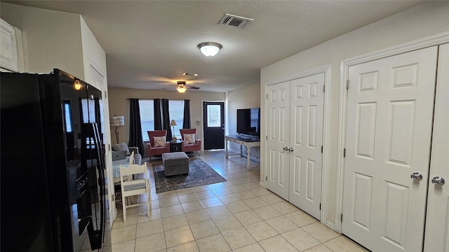 living room featuring light tile patterned floors, a textured ceiling, and ceiling fan